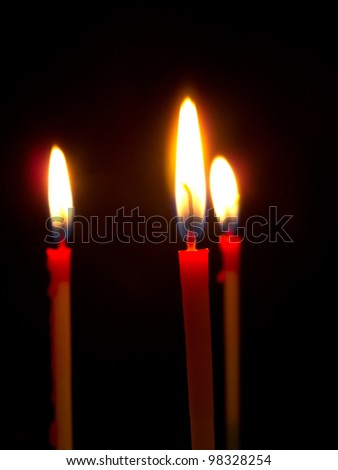 Three red lit  birthday candles against black background.