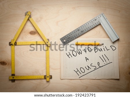 Folding rule setting up in shape of a house on wooden background. House building guidance.