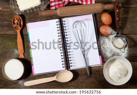 Baking cake in rural kitchen - dough recipe ingredients (eggs, flour, milk, butter, sugar) and rolling pin on vintage wood table from above. Rustic background with free text space.