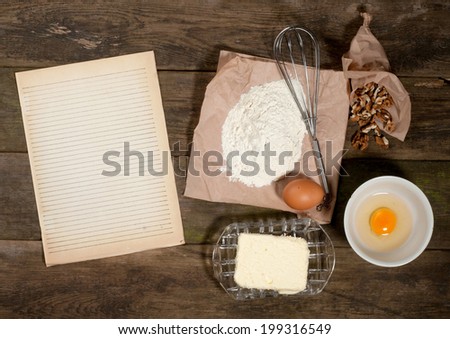 Baking cake in rural kitchen - dough recipe ingredients (eggs, flour, butter, sugar) and rolling pin on vintage wood table from above. Rustic background with free text space.