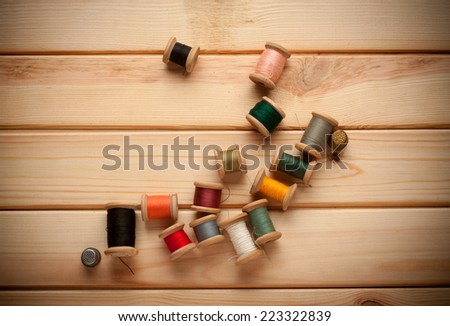 Sewing kit. Scissors, bobbins with thread and needles on the old background