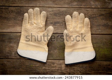A pair work gloves lying on planks of wooden background
