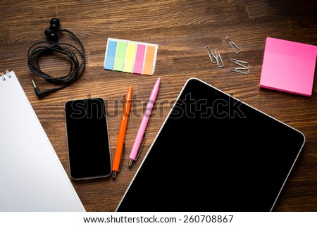 Digital tablet computer with note paper and cup of coffee on old wooden desk. Simple workspace or coffee break with web surfing.