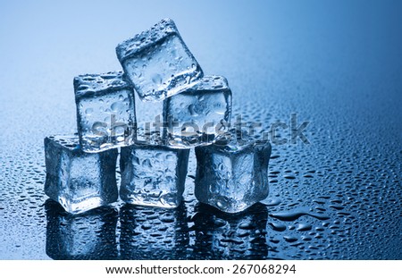 wet ice cubes on blue background with water drops