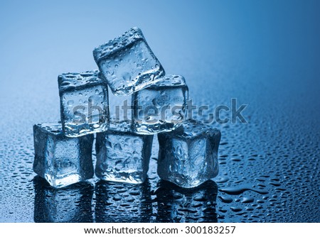 wet ice cubes on blue background with water drops .