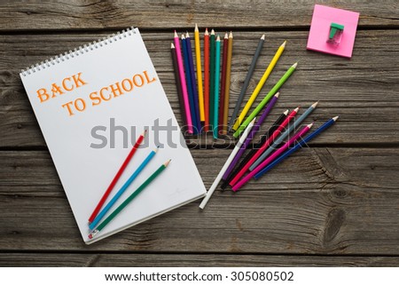 Back to School pupils art pencils and pad on wooden desk from above.