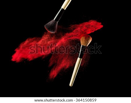 Make-up brush with powder explosion on black background