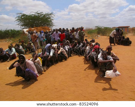 DADAAB, SOMALIA-AUGUST 15: Unidentified men and children wait for relief aid in the Dadaab refugee camp where thousands of Somalis end up due to hunger on August 15, 2011 in Dadaab, Somalia.