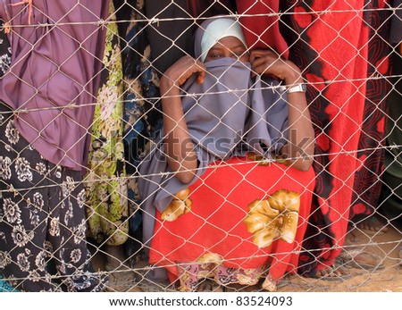 DADAAB, SOMALIA-AUGUST 15: Unidentified women waits behind a fence for relief aid in the Dadaab refugee camp where thousands of Somalis end up due to hunger on August 15, 2011 in Dadaab, Somalia.