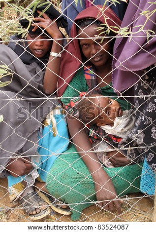 DADAAB, SOMALIA-AUGUST 15: Unidentified men, women & children wait for relief aid in the Dadaab refugee camp where thousands of Somalis end up due to hunger on August 15, 2011 in Dadaab, Somalia.