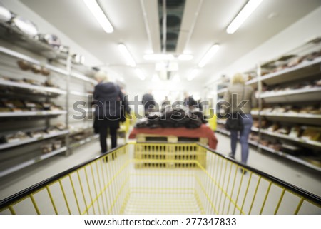Out of focus shot of people shopping in a grocery store setting, shot from the shopping cart, great as a background in designs