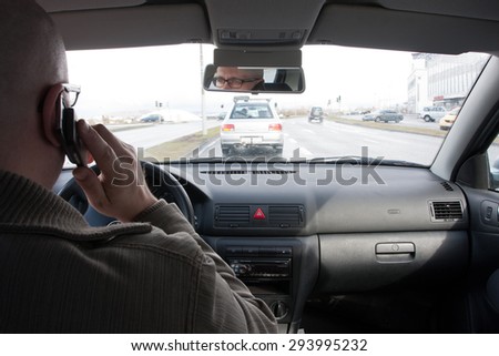 Man on mobile while driving, shot from the backseat