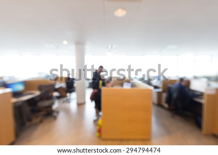 Out of focus shot of office workers working together on a project, overexposed windows in the background