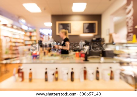 Out of focus shot of a person working at a sales counter in a bookstore / coffee shop
