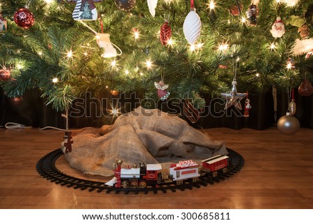 Toy train beneath a decorated christmas tree with christmas lights. starburst forming on lights