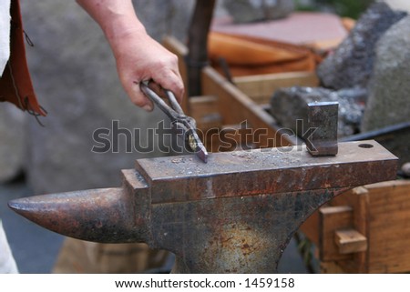A craftsman/blacksmith working metal the oldfashioned way, with hammer and anvil and open fire