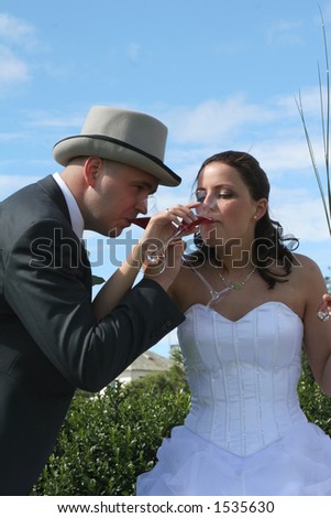 A wedding, toasting and drinking bubbly wine outside in sunny weather, against a clear blue sky