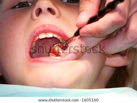 A young boy at the dentists, dentist taking a look into his mouth using various tools