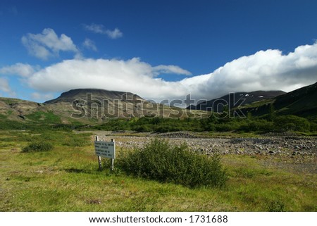 Landscape photo of a valley in a clear weather, sign on ground says, no camping, fishing area