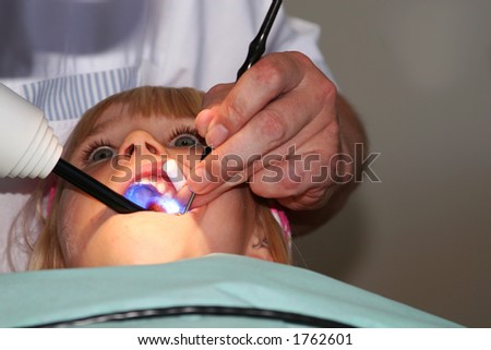 A young girl at the dentists, dentist taking a look into her mouth using various tools