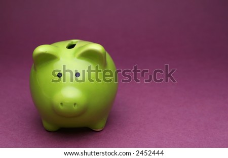 A green piggy bank on purple background, shot from the front