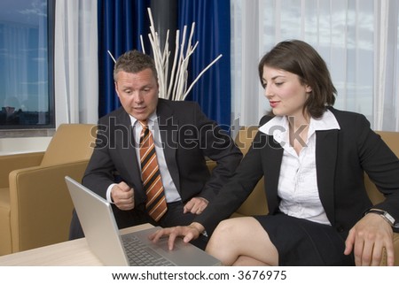 A businessman an businesswoman smartly dressed working on a business deal on a laptop