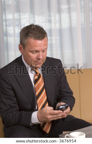 Businessman looking away from camera texting on his mobile phone