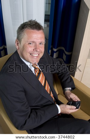 Businessman smiling at camera texting on his mobile phone