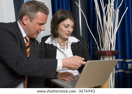 Businessman and businesswoman work on laptop working out something