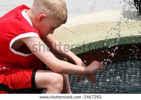 A young boy cooling off in a fountain in the heat of summer