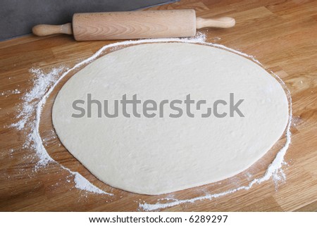 homemade pizza on wooden kitchen counter with rolling pin
