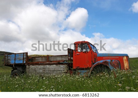 Broken down vintage truck standing in a field of grass in summer