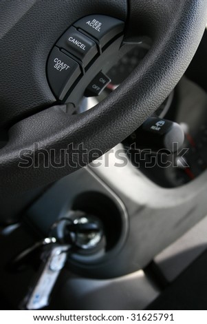 Cropped shot of the controls in a modern car, cruise control, steering wheel, key in ignition and more