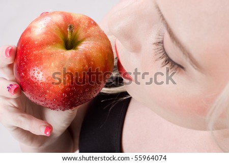 Pretty woman holding a fresh apple with water droplets about to bite into it. Selective focus, very erotic and sensual. Shot from above