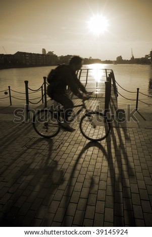 Cycling man against sunset, London, UK