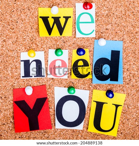 The phrase we need you in cut out magazine letters pinned to a cork notice board