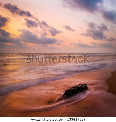 Sunset at tropical beach. Rocks at the ocean coast under evening sun. South India  landscape