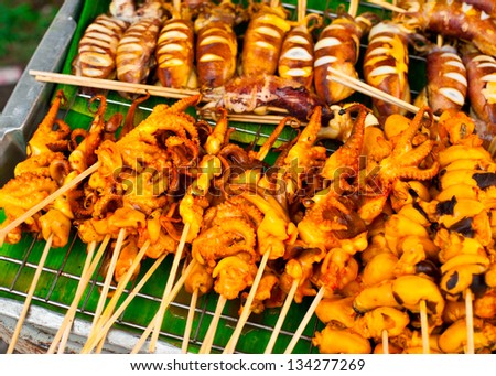 Traditional Thai food at market. Grilled seafood on sticks. Calamari, octopus and cuttlefish