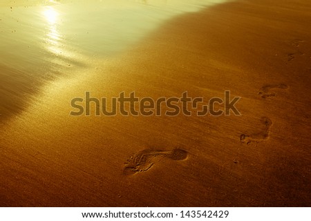 Footprint in sand. Beautiful sunset at tropical ocean beach in vintage style