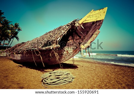 Tropical beach landscape with fishing boat at ocean coast under blue sky. Image in vintage style. India
