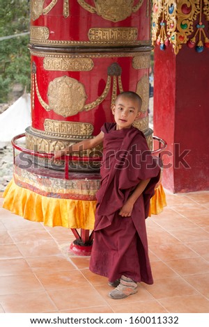 HEMIS, INDIA - SEPTEMBER 13: Unidentified tibetan boy, novice monk, student of Buddhist school at Hemis monastery, rotating praying wheel on September 13, 2012 in Hemis Gompa, Leh, Ladakh, india
