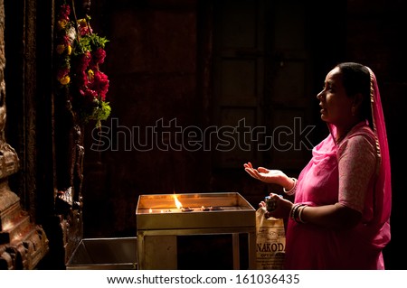 MADURAI, INDIA - FEBRUARY 16: Indian woman in colorful sari prays inside Meenakshi Temple on February 16, 2012. Meenakshi Temple is one of the most holy place for hindu people. India, Madurai