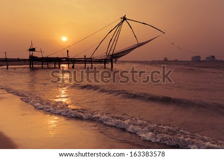 Sunset at tropical beach. Ocean coast landscape with chinese fishing nets silhouette at Cochin (Kochi). South India, Kerala, Kochin