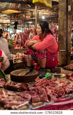 SIEM REAP, CAMBODIA - DEC 22, 2013: Unidentified Khmer woman selling meat at traditional food marketplace on Dec 22, 2013 in Siem Reap, Cambodia. Street food markets is popular tradition in asia