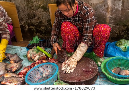 SIEM REAP, CAMBODIA - DEC 22, 2013: Unidentified Khmer woman cleaning and selling fish at food marketplace on Dec 22, 2013 in Siem Reap, Cambodia. Street food markets is popular tradition in asia