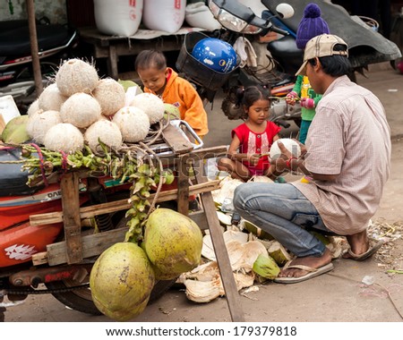 SIEM REAP, CAMBODIA - DEC 22, 2013: Unidentified Khmer family selling coconuts at traditional food marketplace on Dec 22, 2013 in Siem Reap, Cambodia. Street food markets is popular tradition in asia