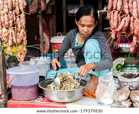 SIEM REAP, CAMBODIA - DEC 22, 2013: Unidentified Khmer woman selling food at traditional food marketplace on Dec 22, 2013 in Siem Reap, Cambodia. Street food markets is popular tradition in Asia