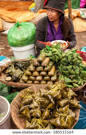 SIEM REAP, CAMBODIA - DEC 22, 2013: Unidentified Khmer woman selling traditional asian food rice in banana leaves on Dec 22, 2013, Siem Reap, Cambodia. Street food markets is popular tradition in asia