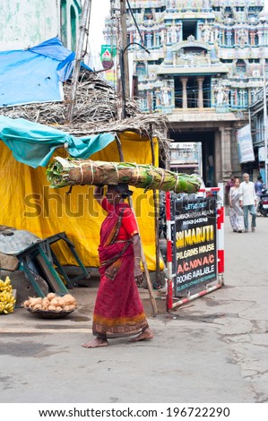 TRICHY, INDIA - FEBRUARY 14:  Indian woman in colorful sari carrying hay bale on head at crowded street near Sri Ranganathaswamy Temple on Febr 14, 2013. South India, Tamil Nadu, Thanjavur (Trichy)