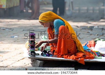KOCHI, INDIA - FEBRUARY 25: Unidentified Indian woman in colorful sari sells souvenirs, bangles and cheap jewelry at street market place on Febr 25, 2013. Fort Cochin (Kochin),  Kerala, India